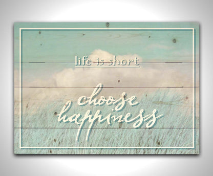 A photo of tall grass under a blue sky with white clouds. The phrase "Life is short, choose happiness" is superimposed on the image. Printed on a wood pallet.