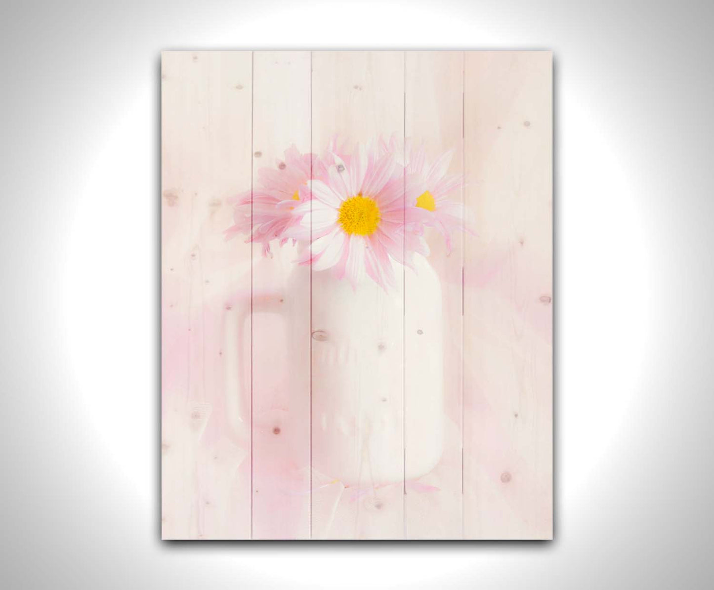 A photo of a white vase with pink daisies in a soft pink background. Printed on a wood pallet.