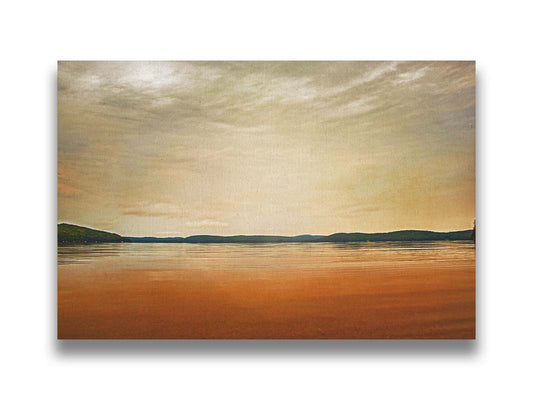 A photograph looking out at the sea and sky. The sky is cloudy and a warm gray, while the sea reflects a brilliant orange. Coastlines of trees can be seen in the distance. Printed on canvas.