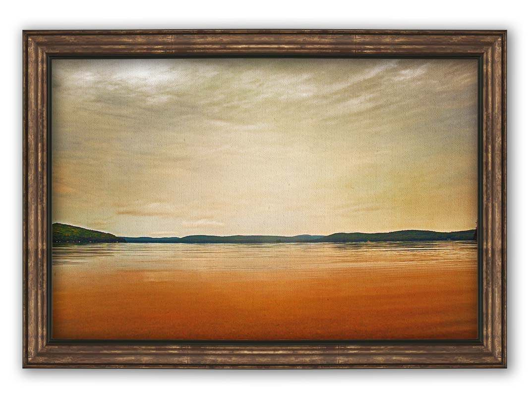 A photograph looking out at the sea and sky. The sky is cloudy and a warm gray, while the sea reflects a brilliant orange. Coastlines of trees can be seen in the distance. Printed on canvas and framed.