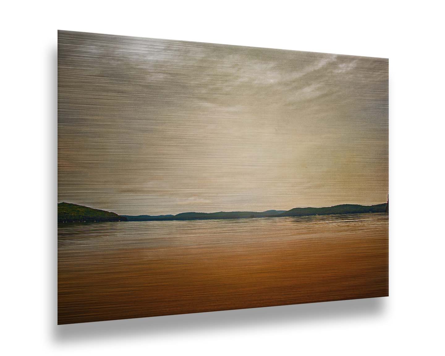 A photograph looking out at the sea and sky. The sky is cloudy and a warm gray, while the sea reflects a brilliant orange. Coastlines of trees can be seen in the distance. Printed on metal.