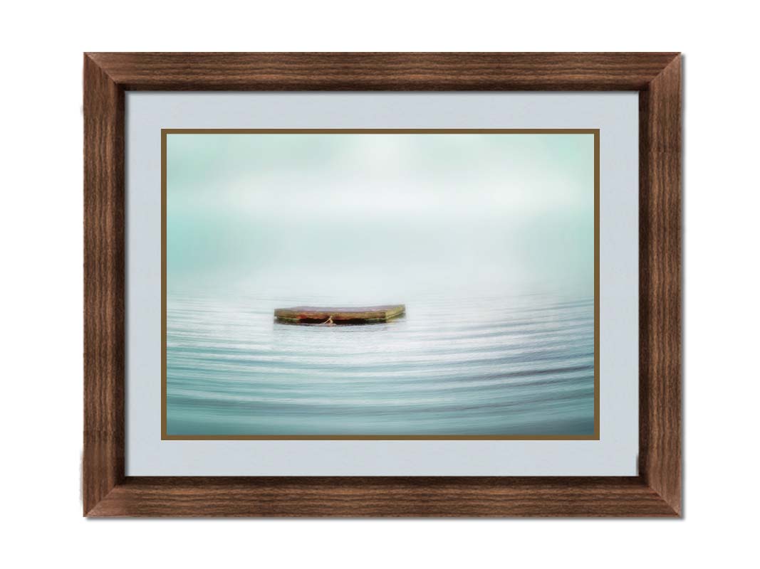 A photo of a small square dock floating on the water. The sky and water blur together. Printed on paper, matted, and framed.