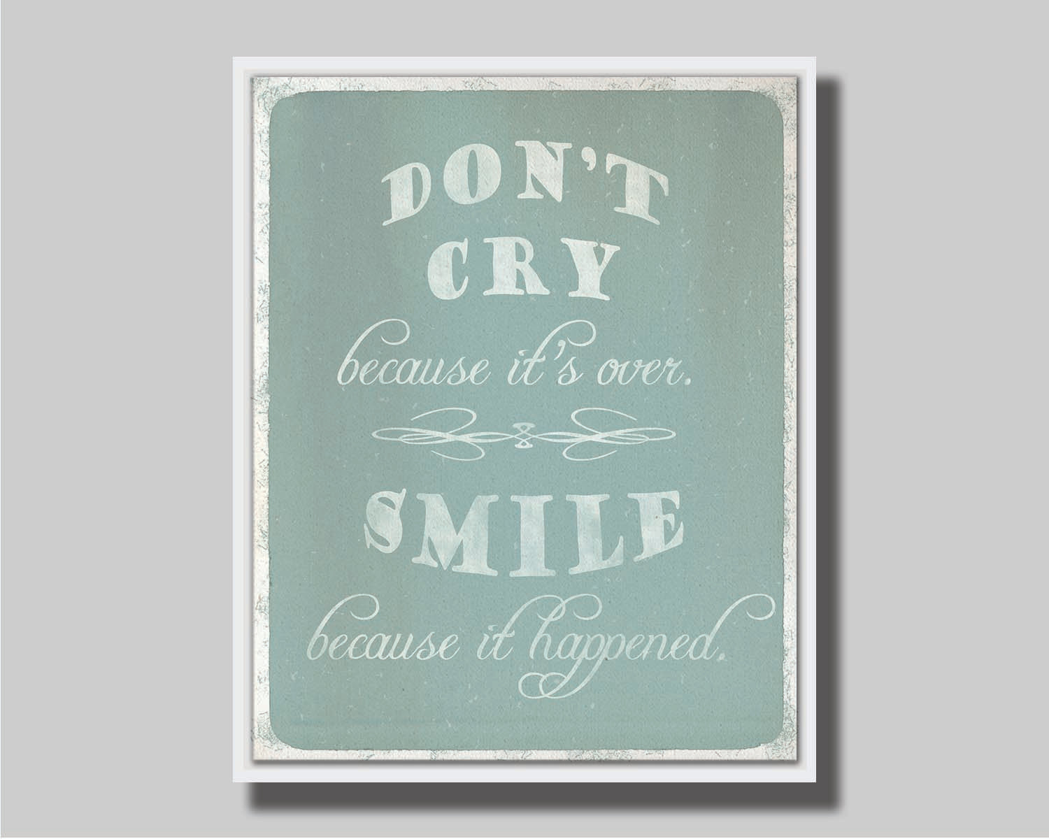 A typography design reading "Don't cry because it's over, smile because it happened" in white on a blue background. Printed on canvas in a float frame.