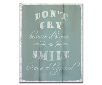 A typography design reading "Don't cry because it's over, smile because it happened" in white on a blue background. Printed on a box board.