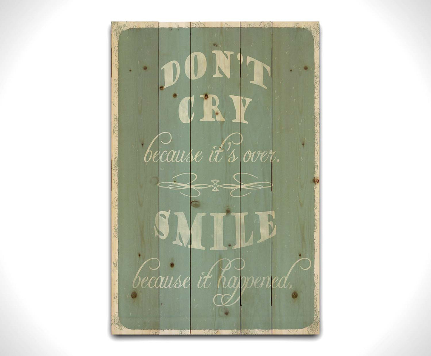 A typography design reading "Don't cry because it's over, smile because it happened" in white on a blue background. Printed on a wood pallet.