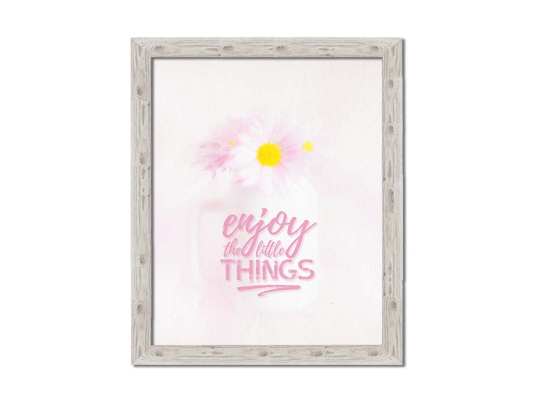 A photo of a white vase with pink daisies in a soft pink background, superimposed with the phrase "enjoy the little things". Printed on canvas and framed.