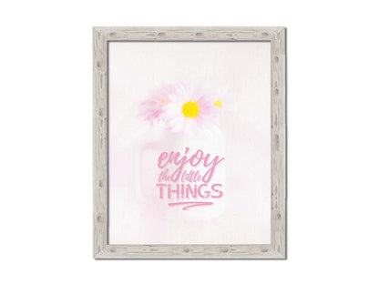 A photo of a white vase with pink daisies in a soft pink background, superimposed with the phrase "enjoy the little things". Printed on canvas and framed.