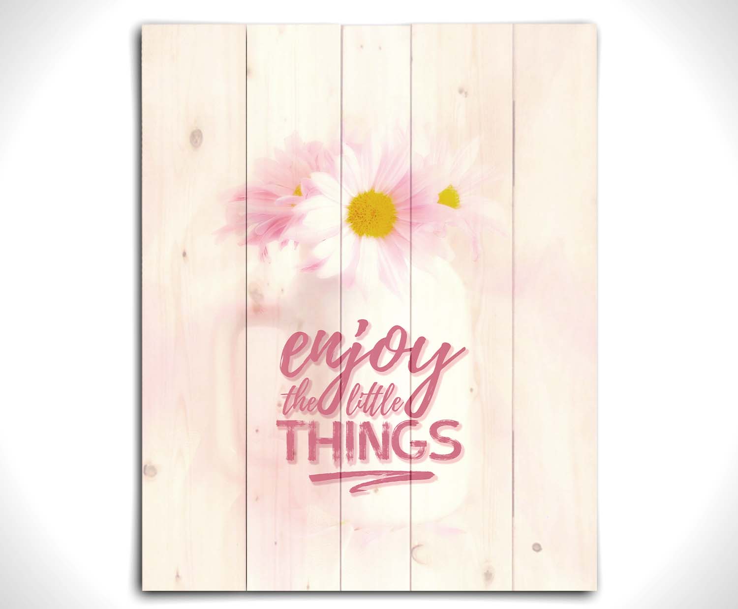 A photo of a white vase with pink daisies in a soft pink background, superimposed with the phrase "enjoy the little things". Printed on a wood pallet.