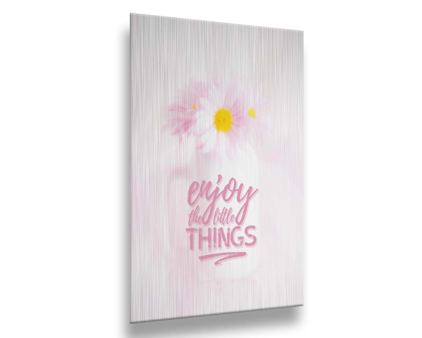 A photo of a white vase with pink daisies in a soft pink background, superimposed with the phrase "enjoy the little things". Printed on metal.