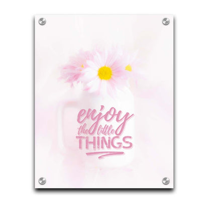 A photo of a white vase with pink daisies in a soft pink background, superimposed with the phrase "enjoy the little things". Printed on acrylic.