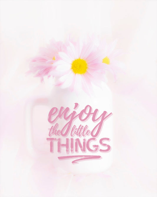 A photo of a white vase with pink daisies in a soft pink background, superimposed with the phrase "enjoy the little things".