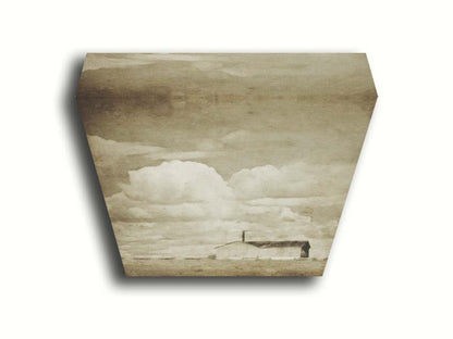 A sepia photo of a barn under a wide, open sky with large, fluffy clouds. Printed on canvas.