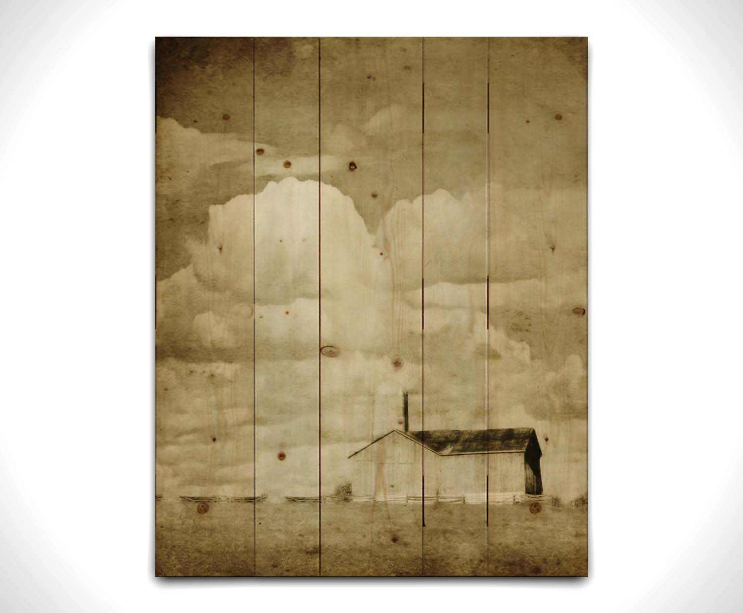 A sepia photo of a barn under a wide, open sky with large, fluffy clouds. Printed on a wood pallet.