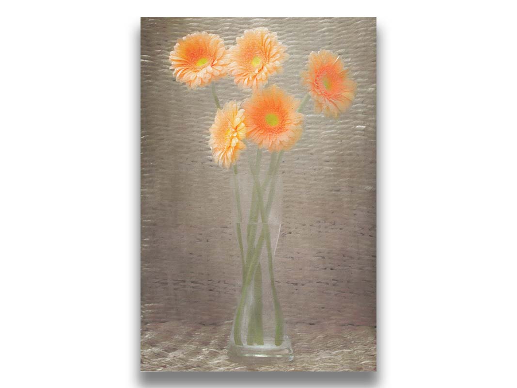 A photo of orange daisies in a vase, sitting in a woven basket. Printed on canvas.