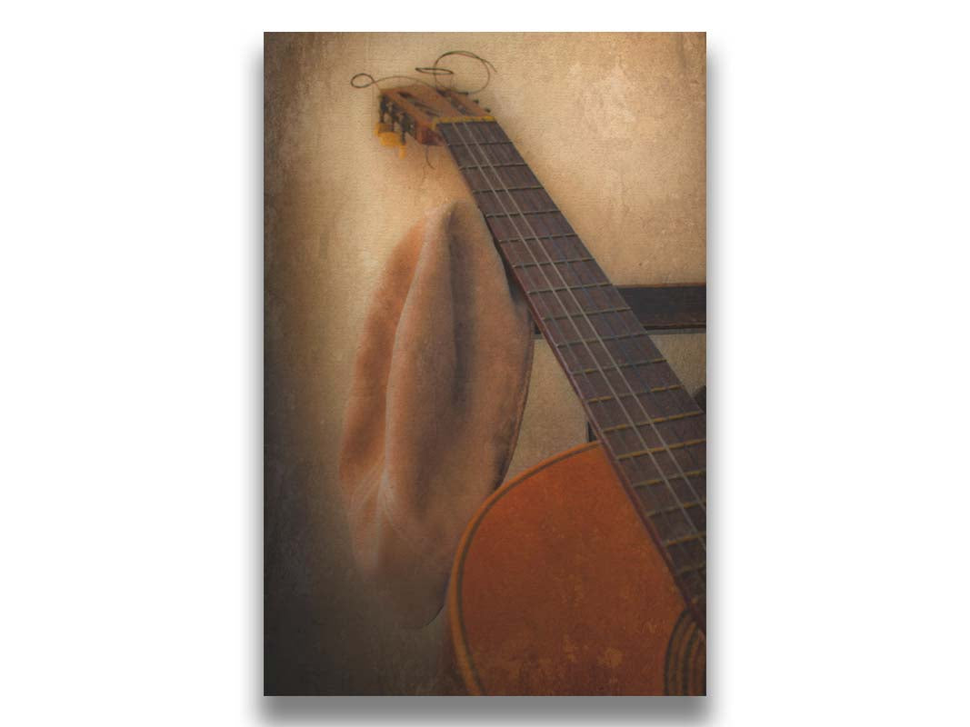 A photo of an acoustic guitar and a hat, sitting on a chair. Printed on canvas.