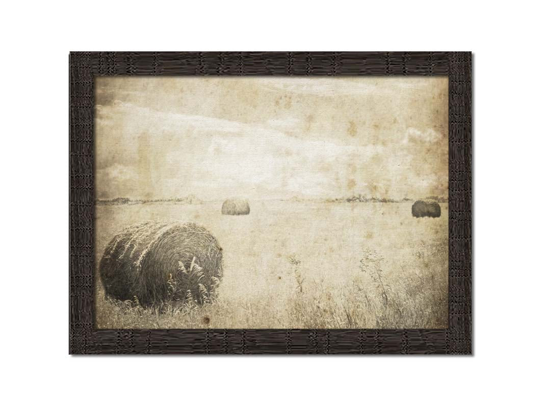 A sepia photo of a wide, open field with several hay bales. Printed on canvas and framed.