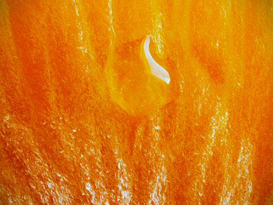 An extreme closeup photo of a drop of liquid on an orange. 