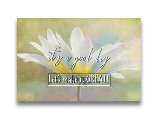 A photo of a white daisy in the sunlight, against a soft green background. It is overlaid with the phrase "It's a good day, let's make it great!" Printed on canvas.