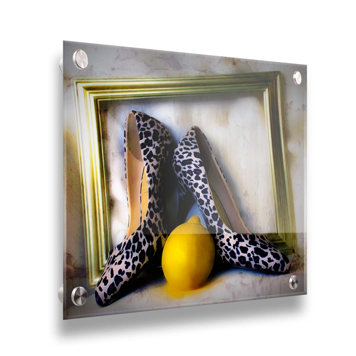 A still life photo of a pair of shoe heels in front of a gold picture frame, accompanied by a lemon. Printed on acrylic.