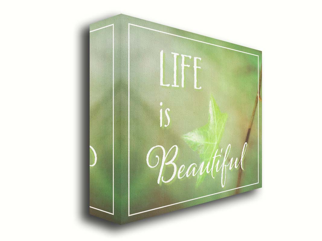 A photograph of a green leaf in soft lighting. The photo is overlaid with white text reading "life is beautiful". Printed on canvas.