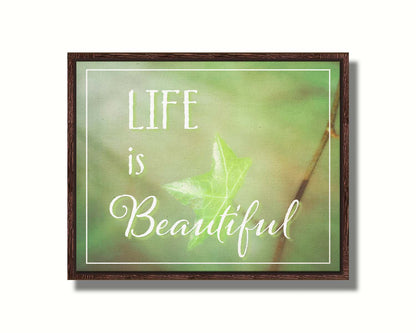 A photograph of a green leaf in soft lighting. The photo is overlaid with white text reading "life is beautiful". Printed on canvas in a float frame.