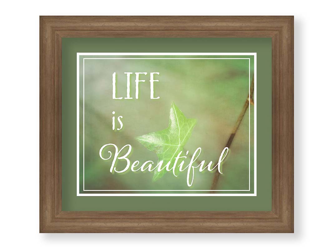 A photograph of a green leaf in soft lighting. The photo is overlaid with white text reading "life is beautiful". Printed on paper, matted, and framed.