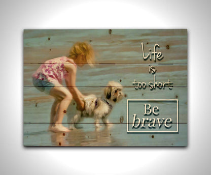 A photograph of a small child and a dog at the beach overlaid with the phrase "life is too short, be brave". Printed on a wood pallet.