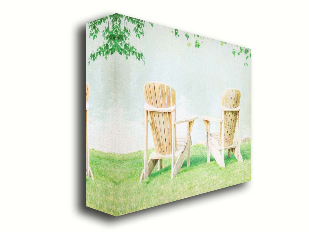 A photo of two wood lawn chairs, sitting on bright green grass, facing a lake. Printed on canvas.