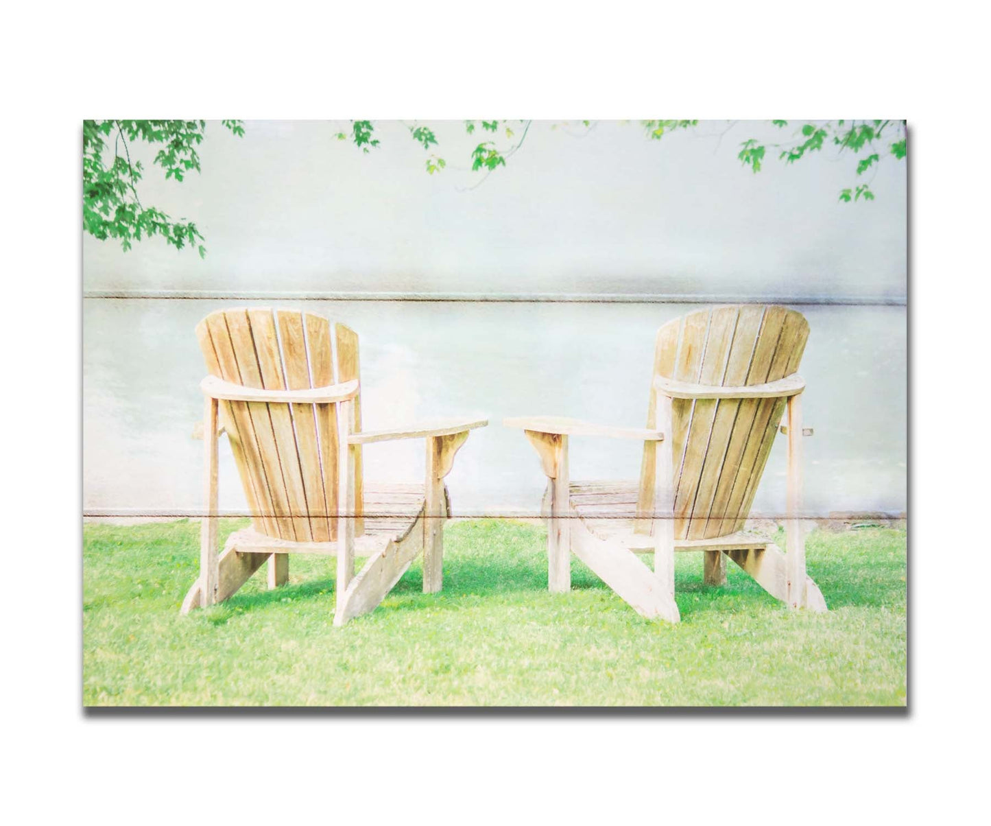 A photo of two wood lawn chairs, sitting on bright green grass, facing a lake. Printed on a box board.