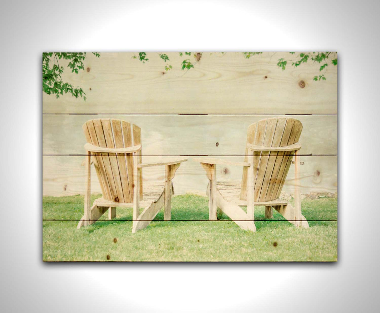 A photo of two wood lawn chairs, sitting on bright green grass, facing a lake. Printed on a wood pallet.