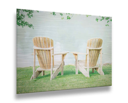 A photo of two wood lawn chairs, sitting on bright green grass, facing a lake. Printed on metal.