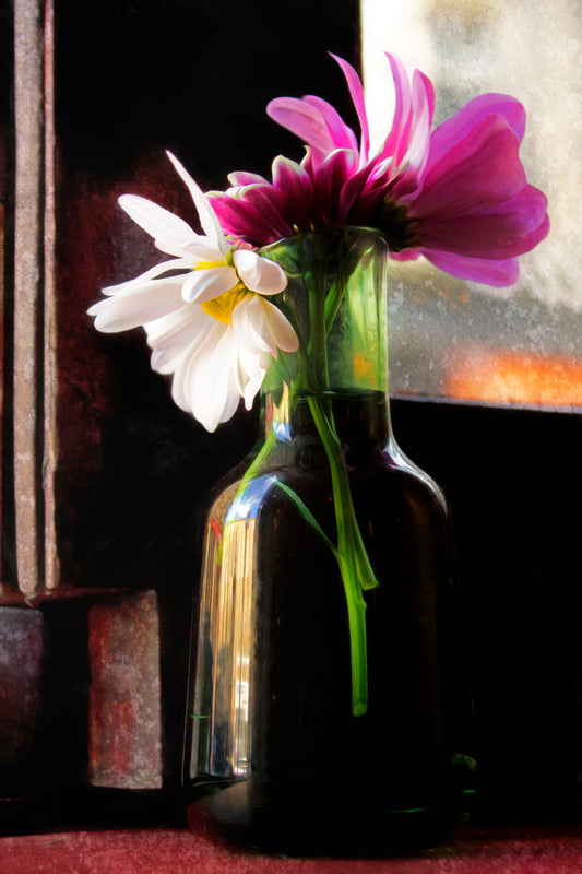 A photo of a few white and pink flowers in a vase, sitting by a window. 