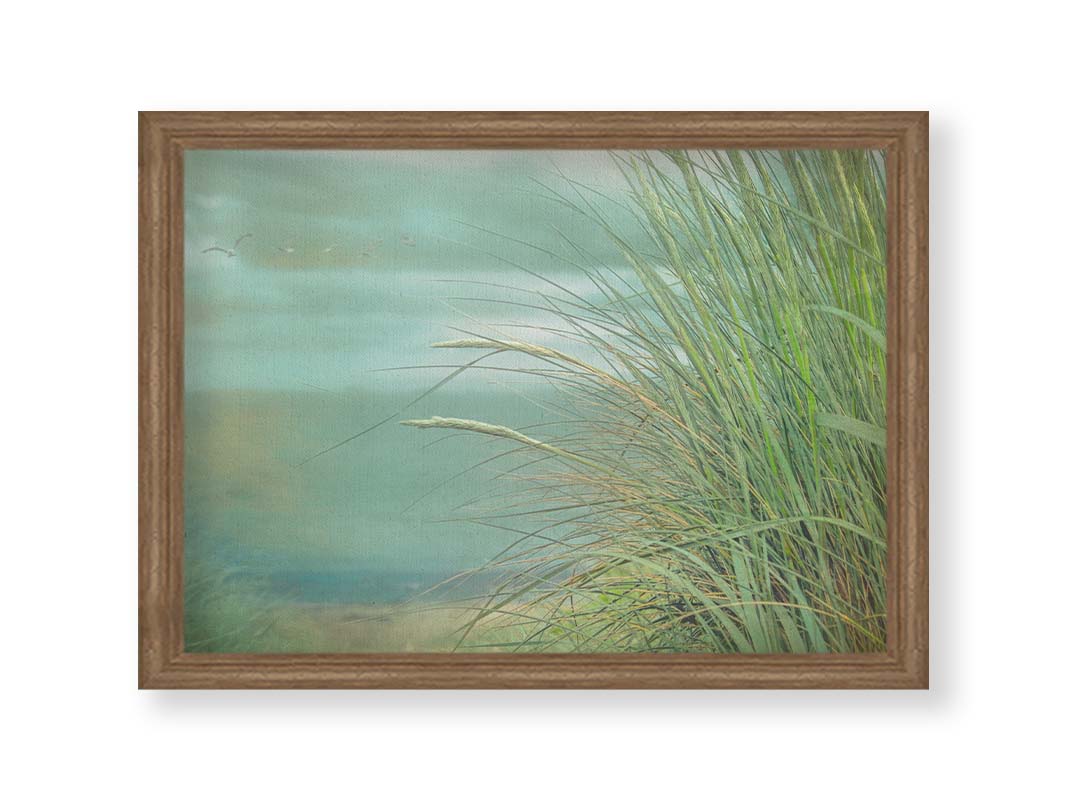 A photo of a tall grass plant on the beach, with the sea and cloudy skies in the background as seagulls fly above. Printed on canvas and framed.