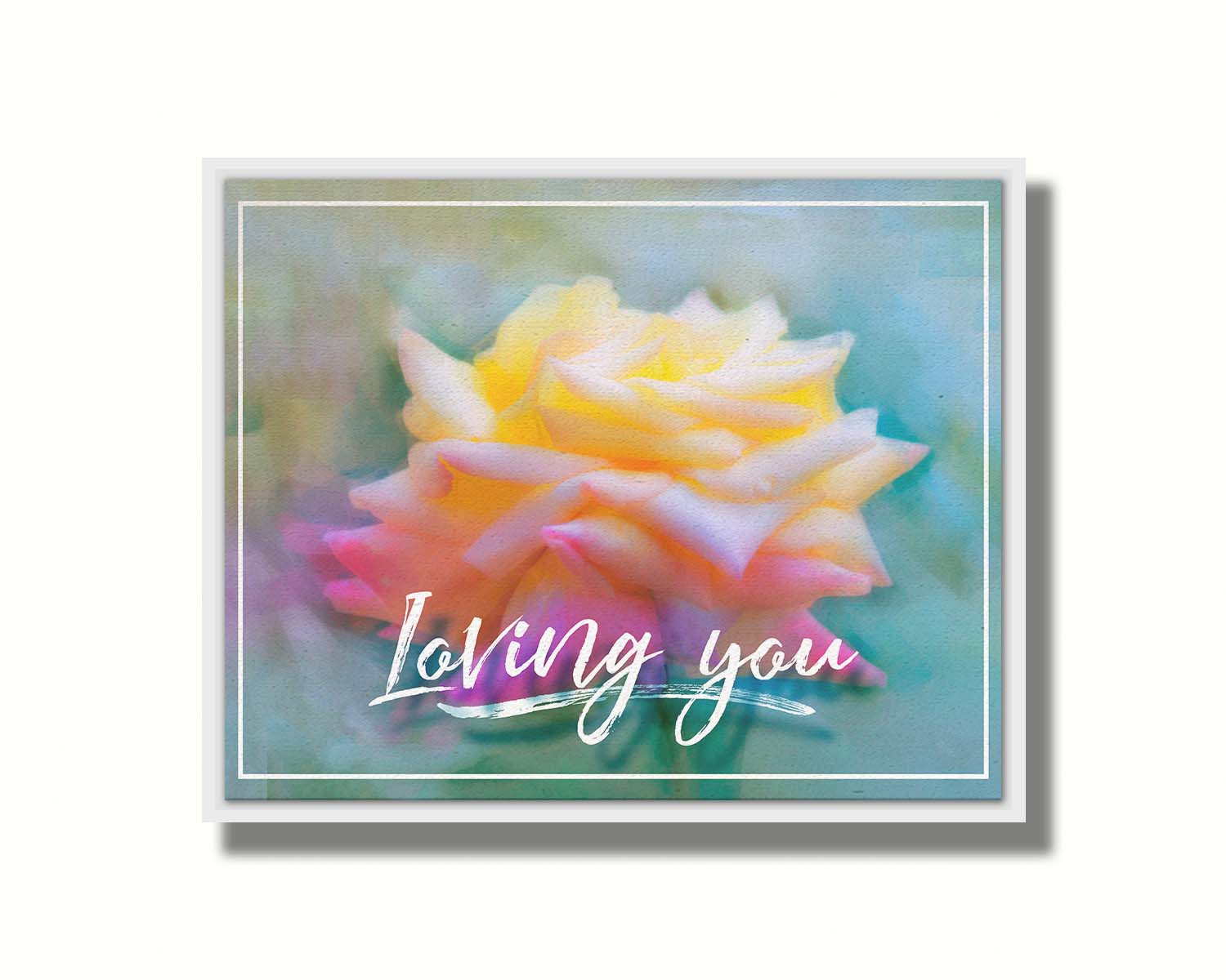 A photo of a pink and yellow rose against a blue background, edited to have a painterly appearance. It is overlaid with a white border and text reading "Loving you." Printed on canvas in a float frame.