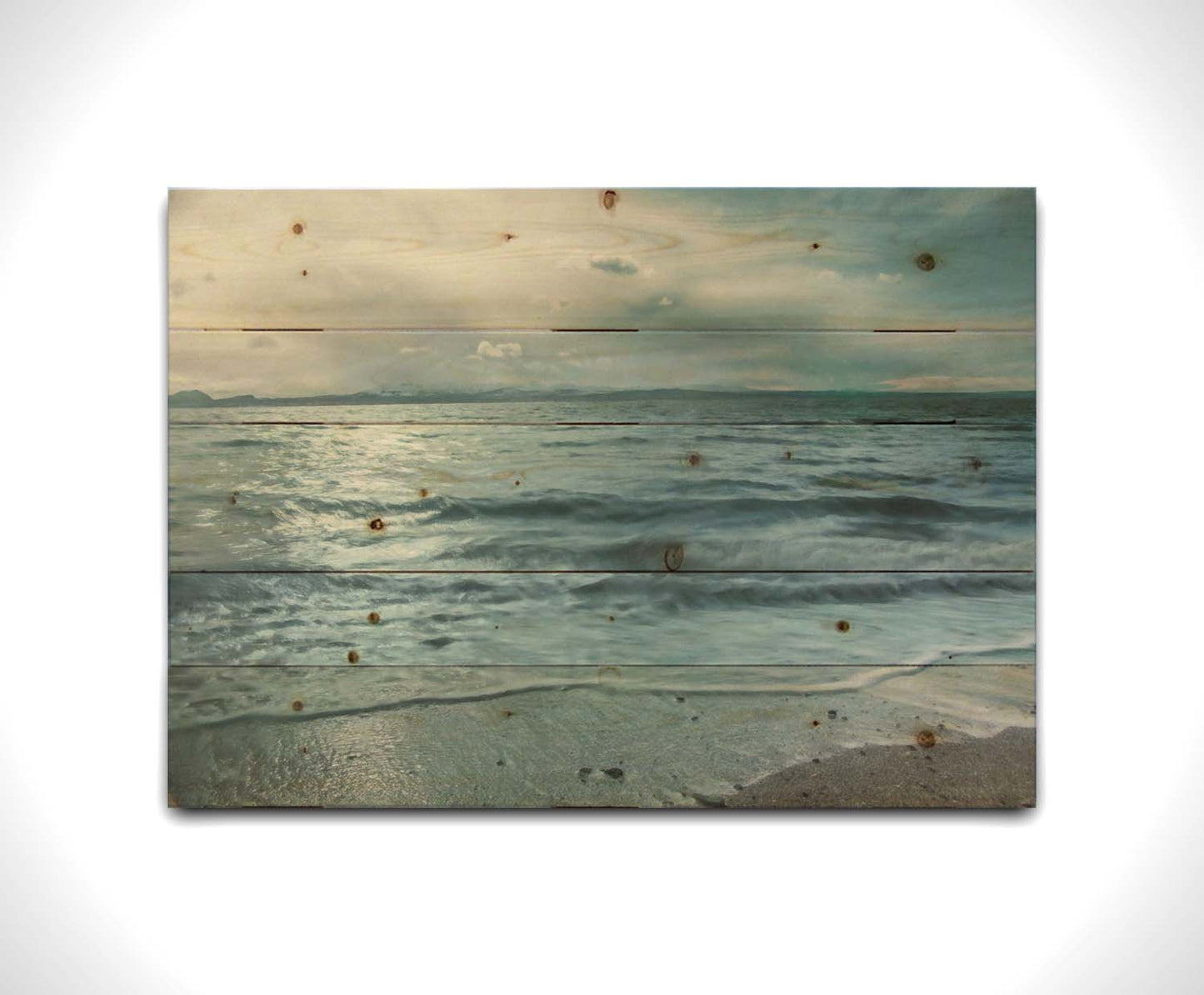 A photo of the sea on a cloudy day, creating a desaturated, stormy look. Printed on a wood pallet.