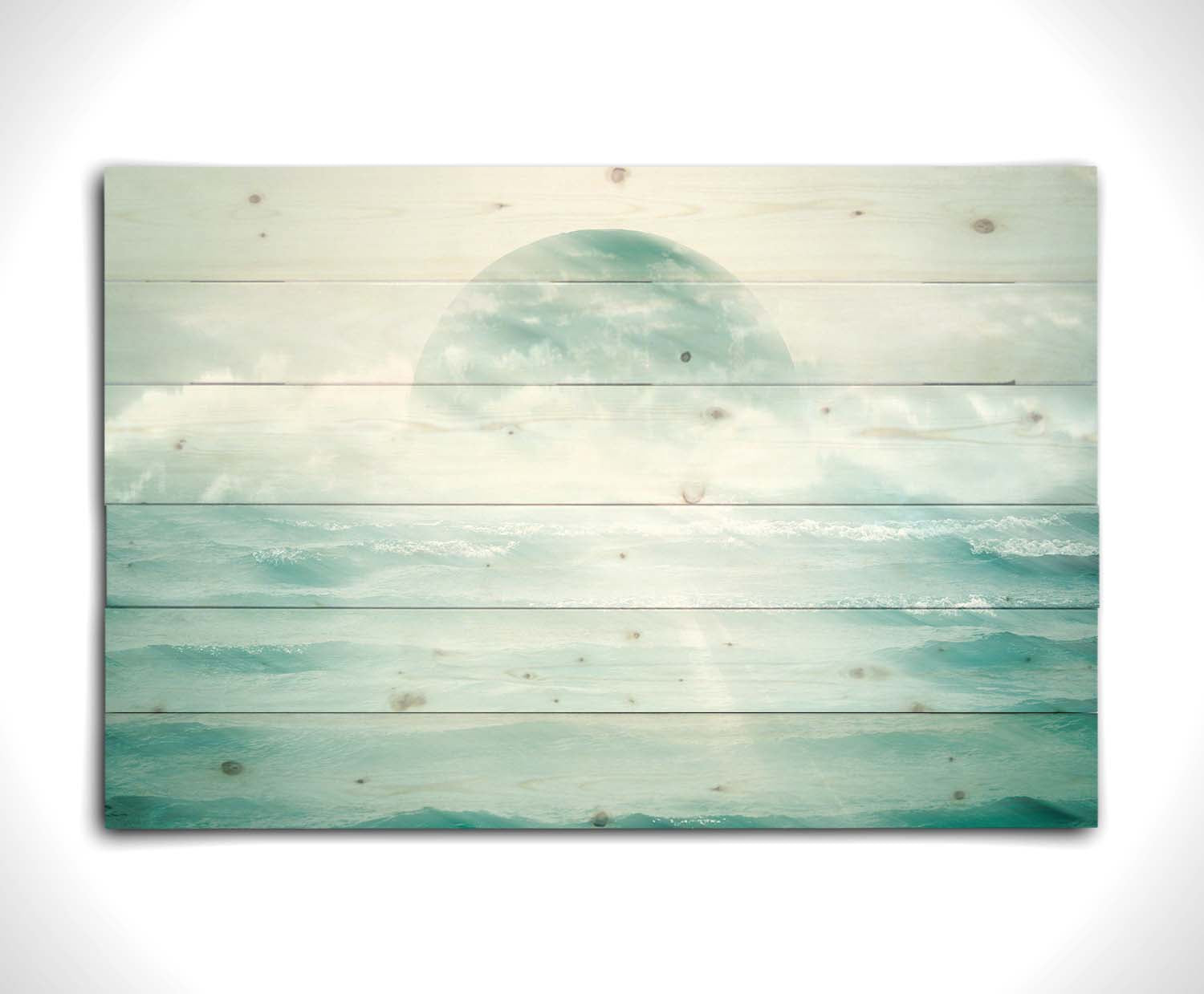 A surreal artistic photography edit of the moon sitting in the ocean. Its light reflects off the water and creates a glow through the fog and clouds just above the water. Printed on a wood pallet.