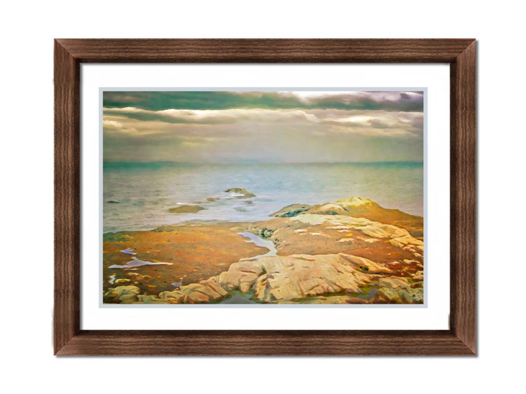 A photo of a stoney shore, looking out to sea under a cloudy sky. Printed on paper, matted, and framed.