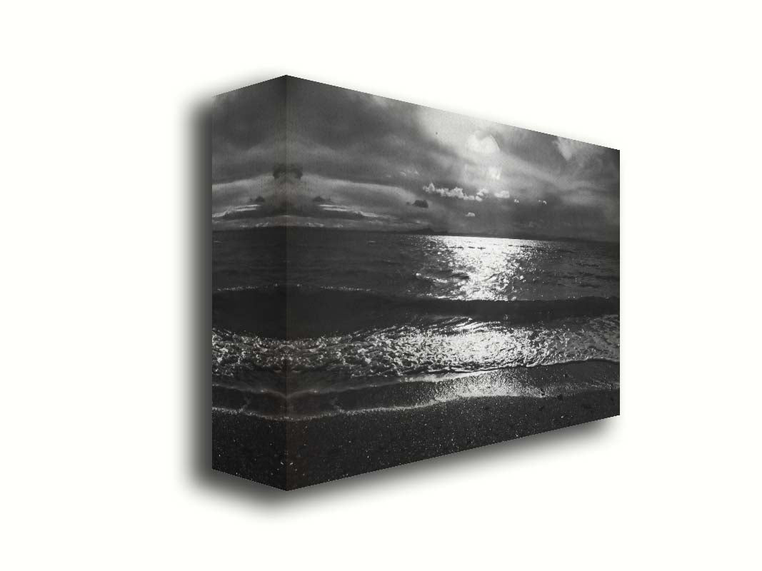 A photograph of the sea at night in grayscale. The light from the moon rerflects off the water in sharp contrast through the darkness of night. Printed on canvas.