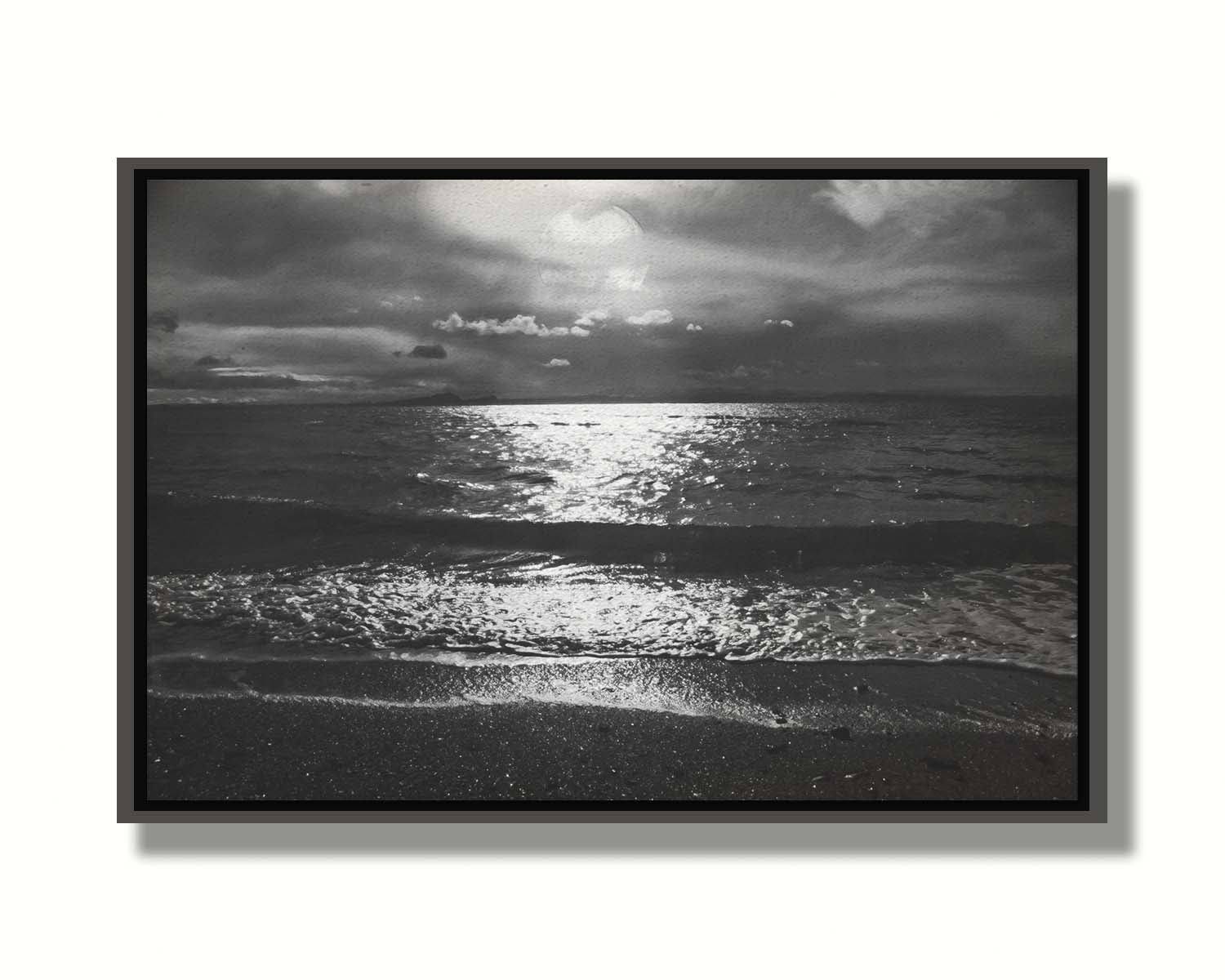 A photograph of the sea at night in grayscale. The light from the moon rerflects off the water in sharp contrast through the darkness of night. Printed on canvas in a float frame.