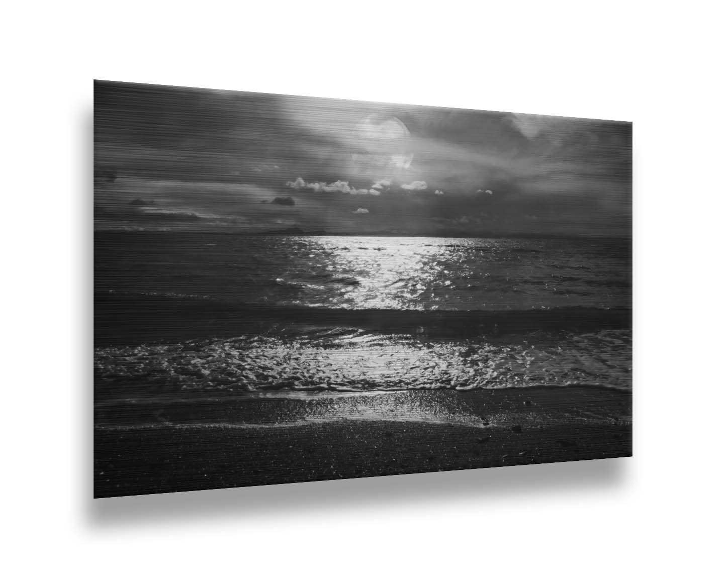 A photograph of the sea at night in grayscale. The light from the moon rerflects off the water in sharp contrast through the darkness of night. Printed on metal.