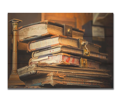 A photo of a stack of worn books, many bound shut by brassy locks. Printed on a box board.