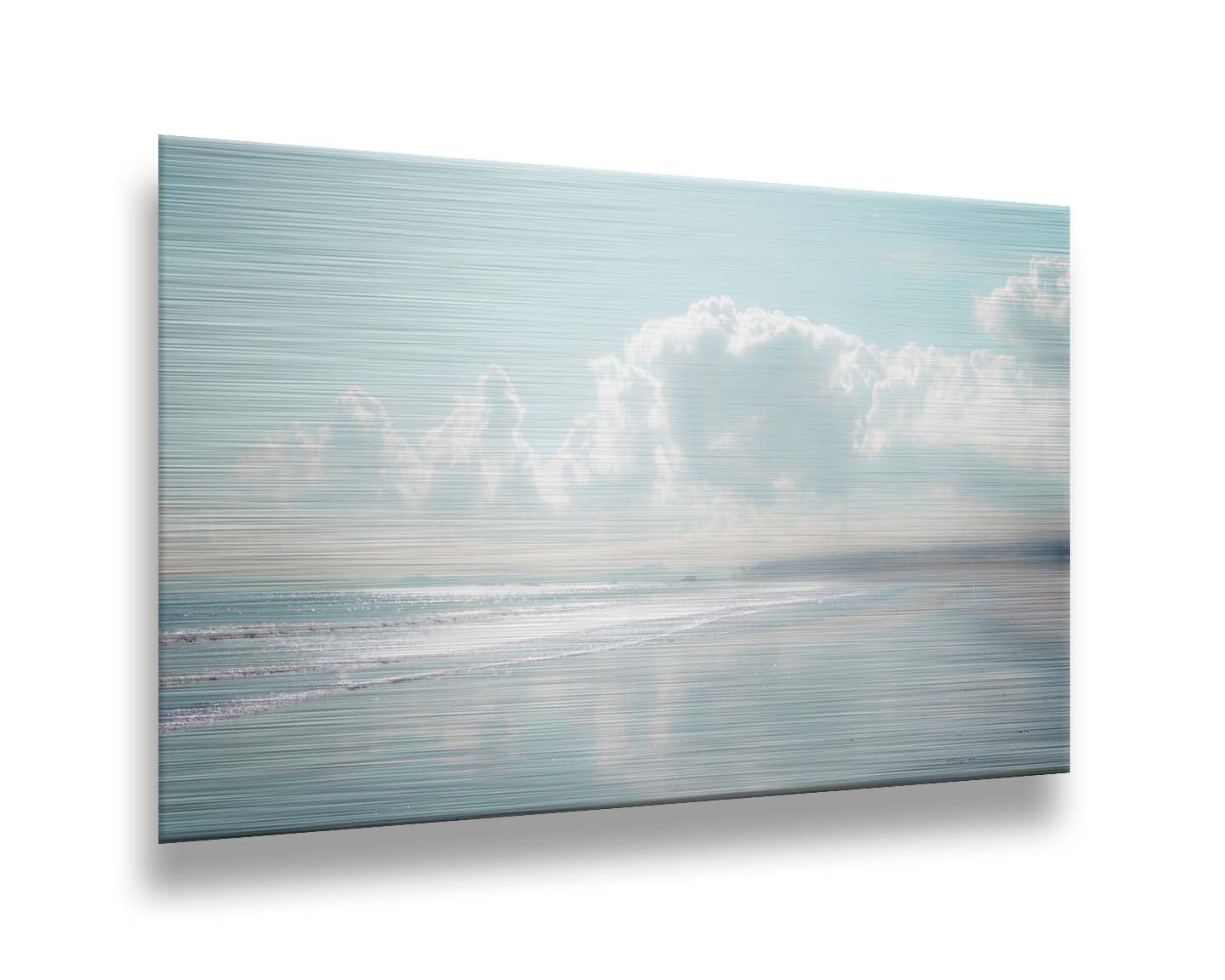 A photo of a beach on a bright but foggy day. The light reflects on the wet sand with the color of the sky,, adding to the dreamlike appearance. A city can be seen through the fog in the distance. Printed on metal.