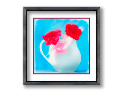 A photo of two red flowes in a white pitcher vase against a cyan backgrround. Printed on paper, matted, and framed.