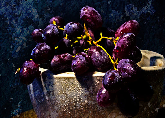 A photo of a bunch of purple grapes in a bowl, covered in drops of water and overlaid with textures.