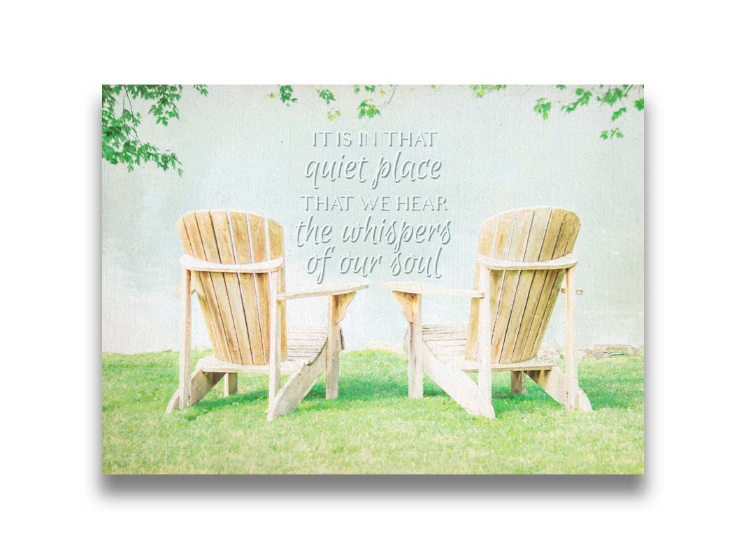 A photo of two wood lawn chairs, sitting on bright green grass, facing a lake. It is overlaid with the phrase, "It is in that quiet place that we hear the whispers of our soul." Printed on canvas.