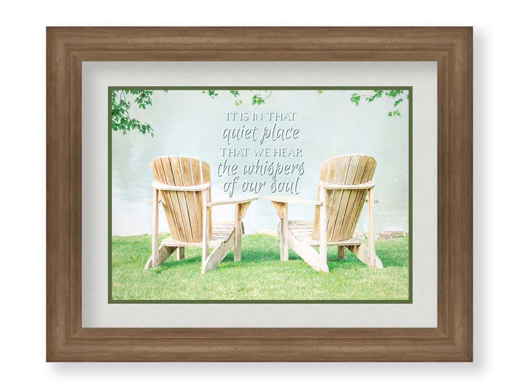 A photo of two wood lawn chairs, sitting on bright green grass, facing a lake. It is overlaid with the phrase, "It is in that quiet place that we hear the whispers of our soul." Printed on paper, matted, and framed.