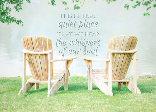 A photo of two wood lawn chairs, sitting on bright green grass, facing a lake. It is overlaid with the phrase, "It is in that quiet place that we hear the whispers of our soul."