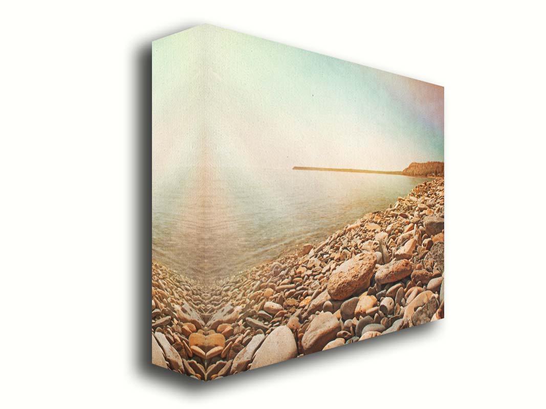 A warm-colored photograph of a rocky beach in the sunlight, bathed in a spectrum of colors. Printed on canvas.