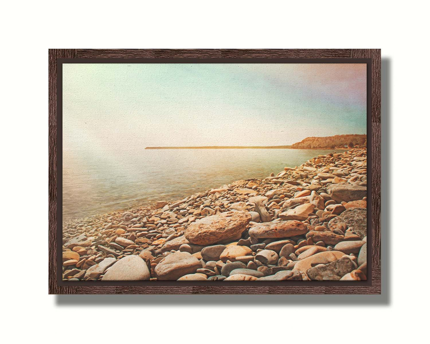 A warm-colored photograph of a rocky beach in the sunlight, bathed in a spectrum of colors. Printed on canvas in a float frame.