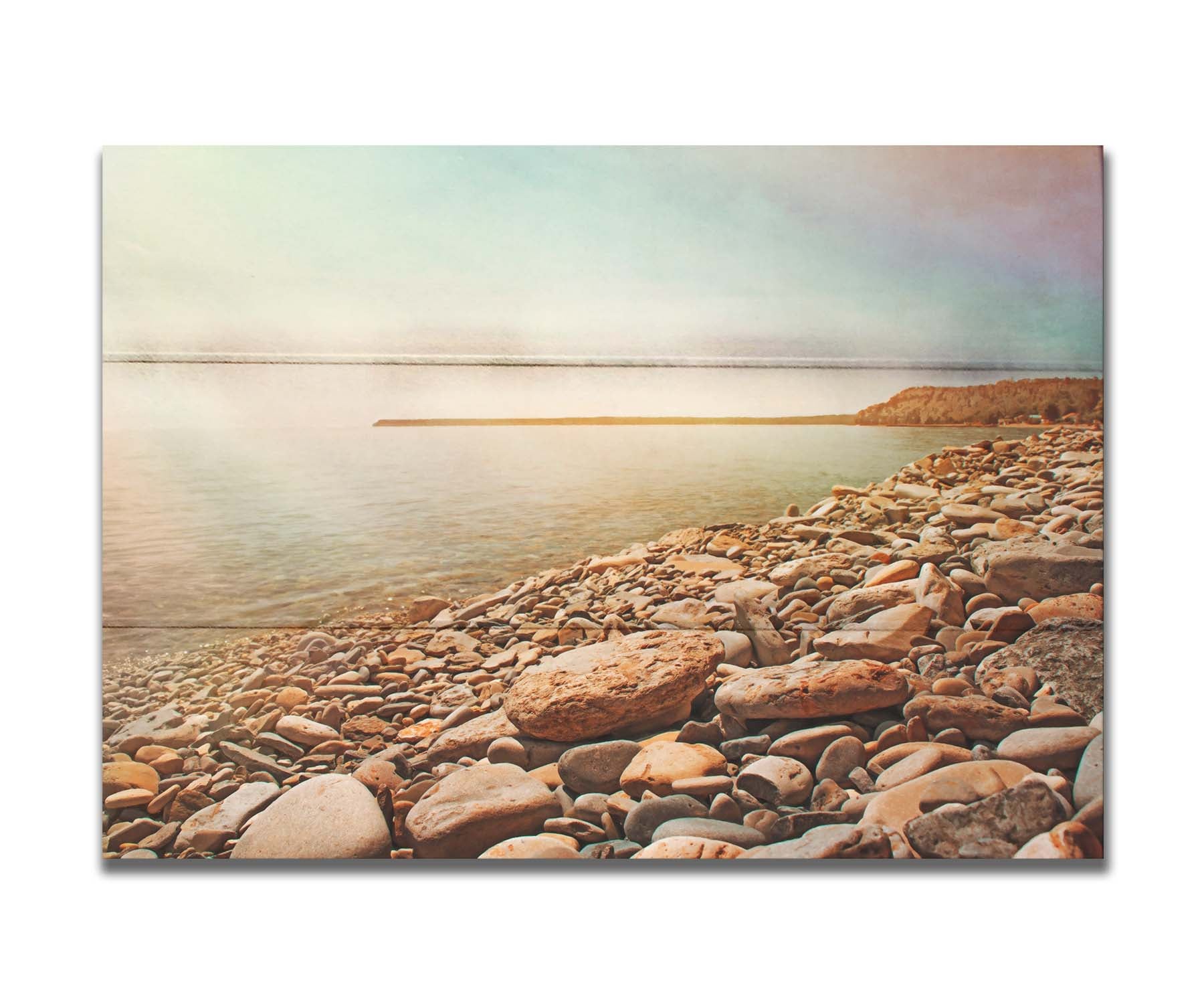 A warm-colored photograph of a rocky beach in the sunlight, bathed in a spectrum of colors. Printed on a box board.